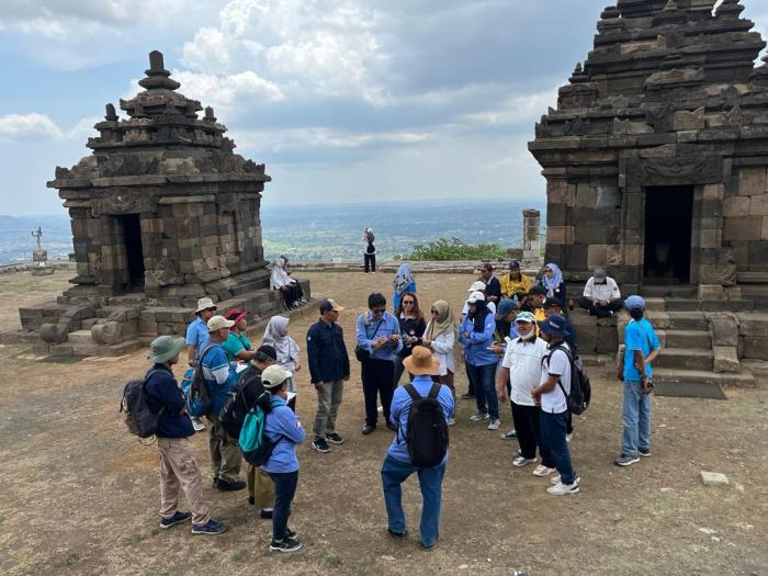 Peserta field trip mendengarkan pemaparan dari kak Mara di Candi Ijo dengan pemandangan yang mengarah ke kota Jogja